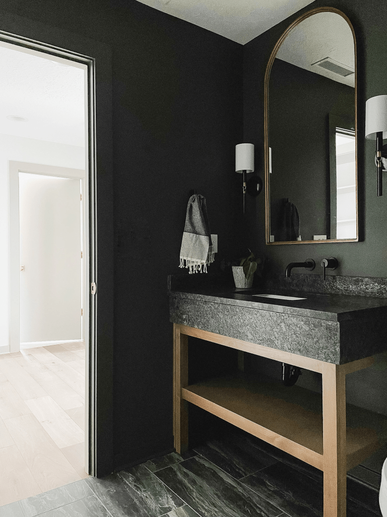 Modern bathroom with dark walls, sleek stone vanity, and stylish mirror, showcasing a functional design ideal for remodeling projects in Salem.